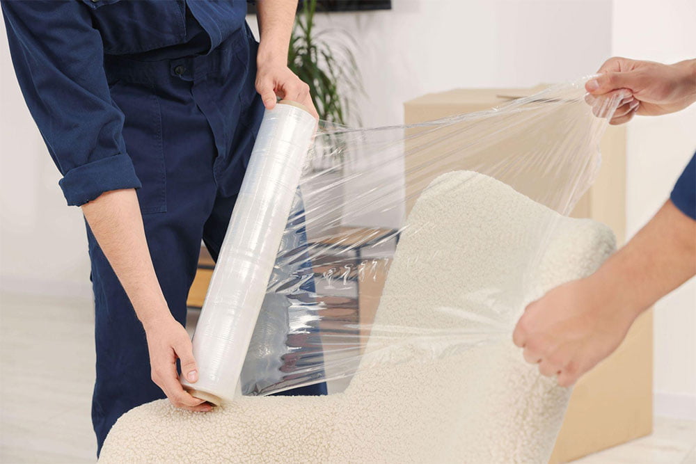 Movers wrapping furniture for protection during a move in Bridlewood, Calgary