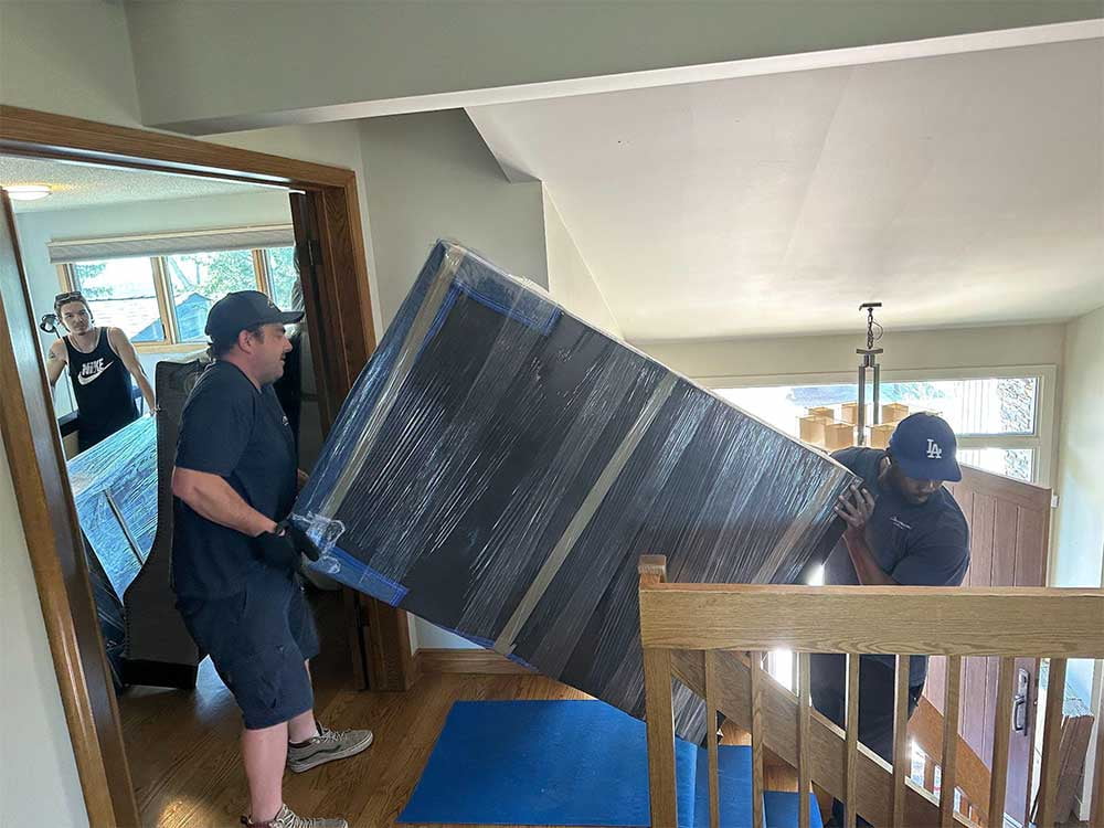 Movers carrying wrapped furniture in Seton, Calgary