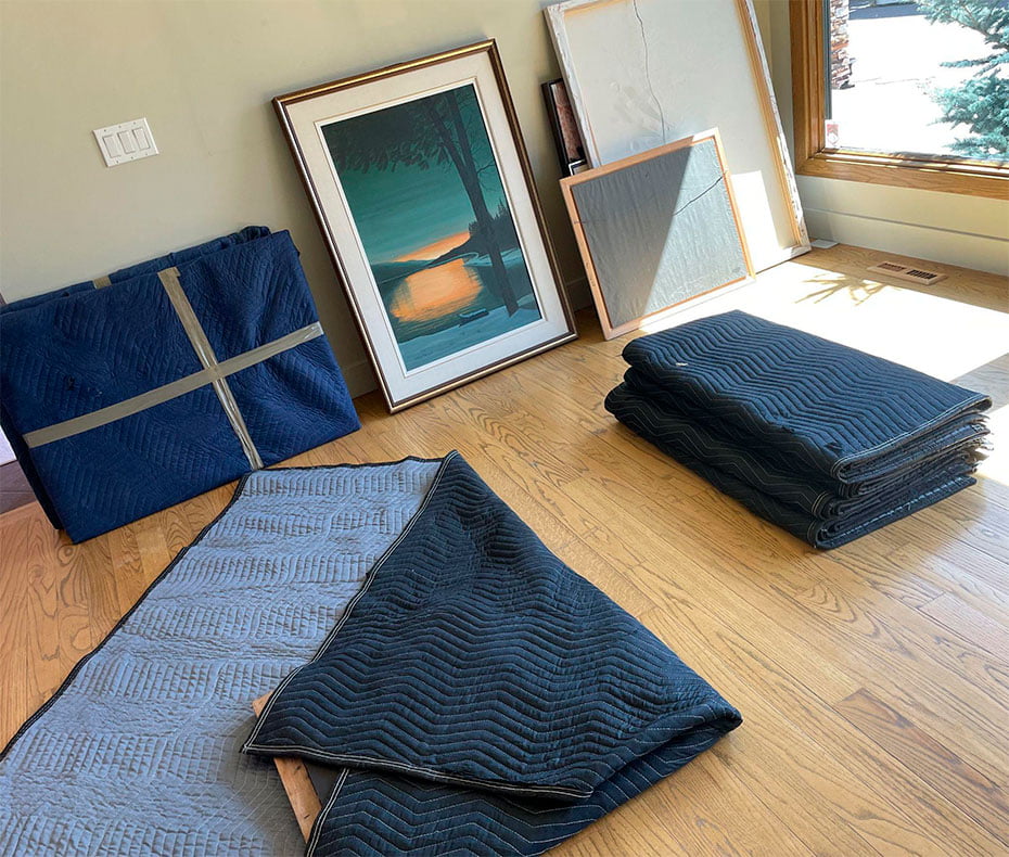 Framed artwork and canvas paintings wrapped in protective moving blankets and prepared for specialty item moving service in Calgary.