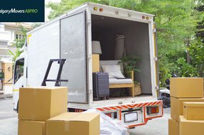 Moving truck loaded with furniture and boxes, parked outside a residential home surrounded by greenery, showcasing a smooth moving process in Calgary