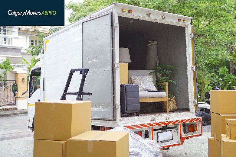 Moving truck loaded with furniture and boxes, parked outside a residential home surrounded by greenery, showcasing a smooth moving process in Calgary
