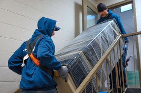 Professional movers carrying a wrapped sofa up a staircase during a residential move in Calgary.