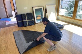 Mover wrapping furniture with protective moving blankets in a home