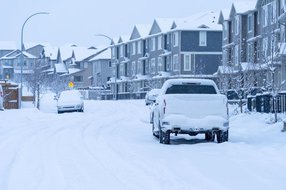 Calgary winter moving conditions — snow-covered residential street with parked cars and townhouses after heavy snowfall in Alberta, Canada
