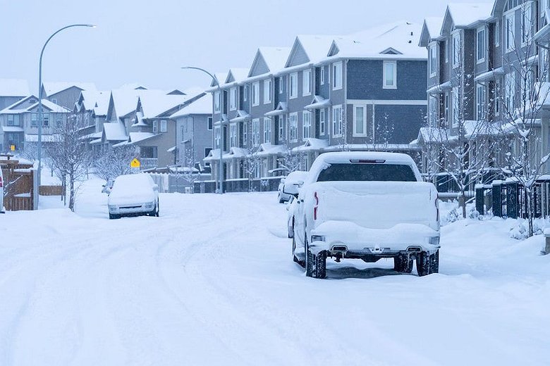 Calgary winter moving conditions — snow-covered residential street with parked cars and townhouses after heavy snowfall in Alberta, Canada